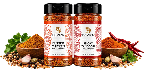 Two Devira spice jars on a white background, surrounded by whole spices, garlic, parsley, and red chilies. The left jar is Butter Chicken Masala Blend, and the right jar is Smoky Tandoori Grill Masala.