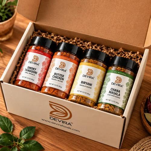 Devira spice blend collection featuring Biryani Masala, Butter Chicken Masala, Chana Masala, and Smoky Tandoori in glass jars with a branded gift box and assorted spices.