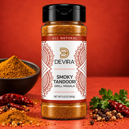 A bottle of Devira Smoky Tandoori Grill Masala spice mix centered on a warm red-orange background, with a bowl of powder, dried red chilies, and parsley around it.